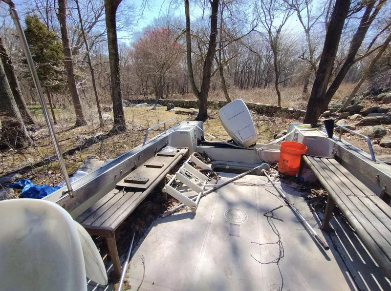 Slide: The Image of 1983 Boston Whaler 25 Revenge boat in wooded area, showing interior seating and equipment. - 25