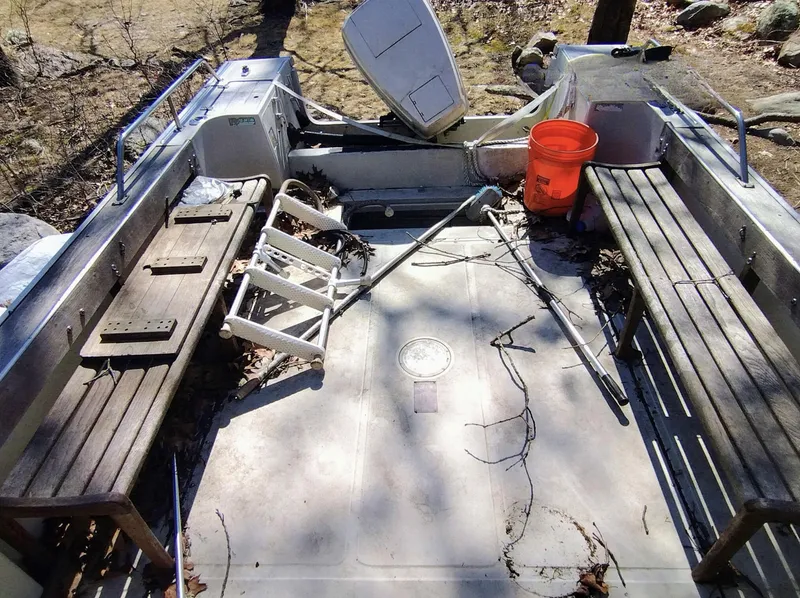 Slide: The Image of 1983 Boston Whaler 25 Revenge interior with benches, orange bucket, and scattered equipment. - 27