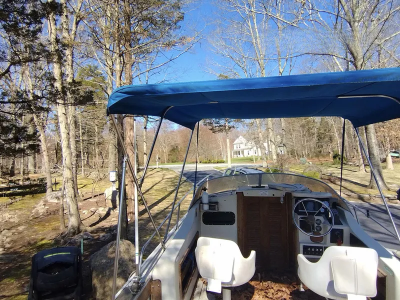 Slide: The Image of 1983 Boston Whaler 25 Revenge boat with blue canopy, parked in a wooded area. - 29