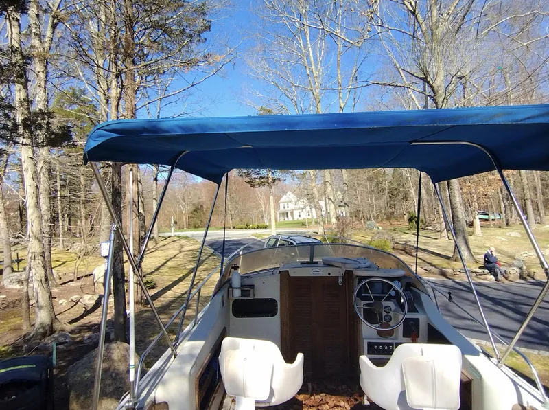 Slide: The Image of 1983 Boston Whaler 25 Revenge boat with blue canopy, parked on a scenic road. - 30