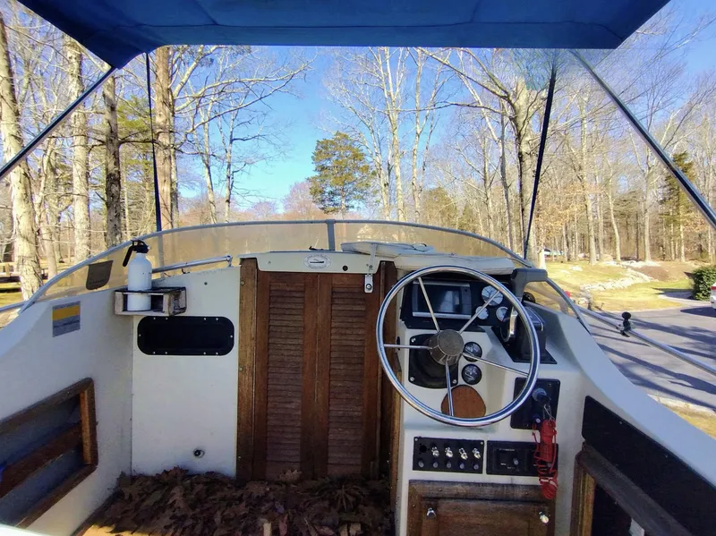 Slide: The Image of 1983 Boston Whaler 25 Revenge boat cockpit with steering wheel, wooden doors, and outdoor setting. - 31