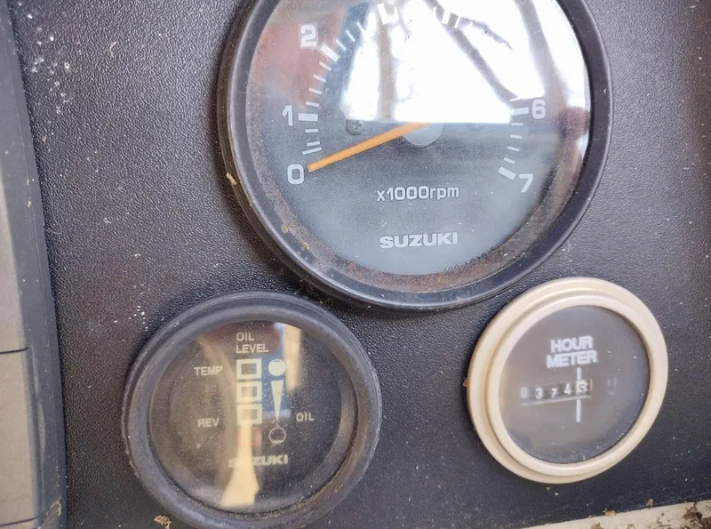 Slide: The Image of Dashboard gauges of a 1983 Boston Whaler 25 Revenge boat, featuring Suzuki instruments. - 34