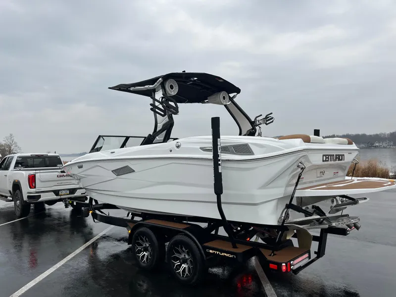 Slide: The Image of 2025 Centurion NV213 boat on trailer, parked near a lake on a cloudy day. - 7