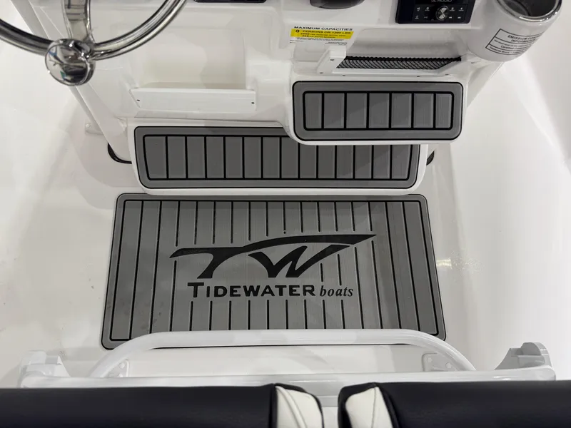 Slide: The Image of 2025 Tidewater 210LXF boat interior with branded flooring and steering wheel. - 21