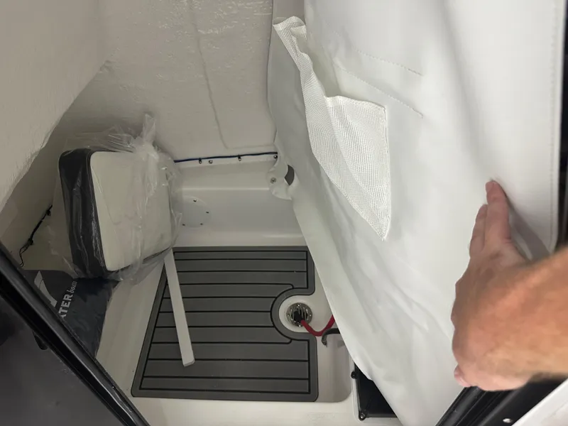 Slide: The Image of 2025 Tidewater 220LXF boat interior storage compartment with white lining and accessories. - 36