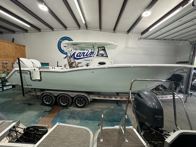 Slide: The Image of 2025 Tidewater 320cc boat in showroom, triple-axle trailer, Yamaha outboard motor. - 1