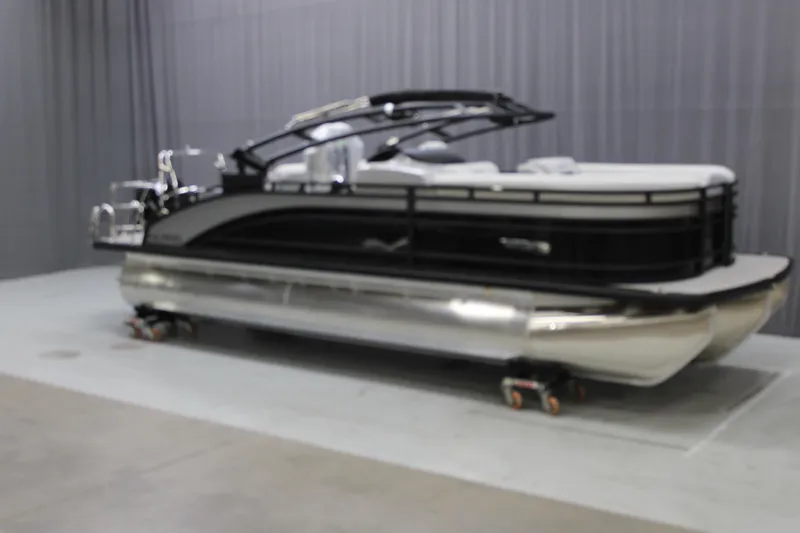 Slide: The Image of 2025 Harris Solstice 230 pontoon boat in showroom, sleek design, black and silver finish. - 2