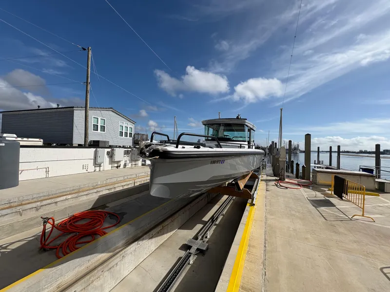 Slide: The Image of 2023 Axopar 28 AFT CABIN boat on dock under clear sky. - 2
