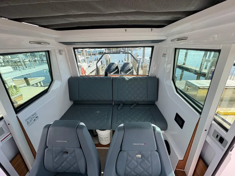 Slide: The Image of 2023 Axopar 28 AFT CABIN interior with seating and waterfront view. - 23