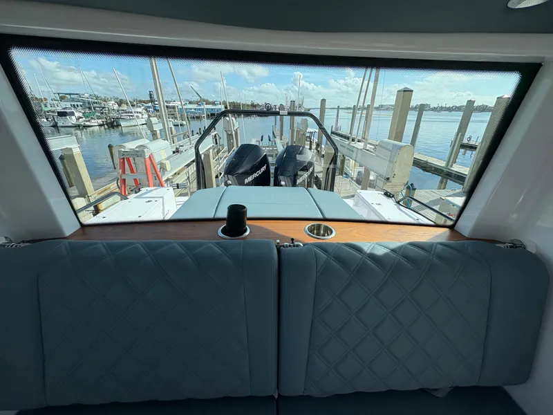 Slide: The Image of Interior view of 2023 Axopar 28 AFT CABIN overlooking marina through rear window. - 24