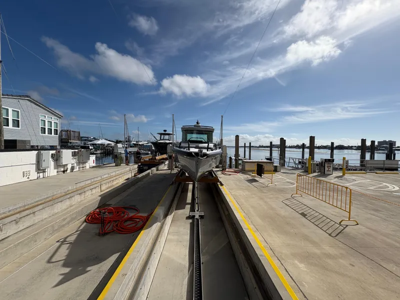Slide: The Image of 2023 Axopar 28 AFT CABIN boat at a marina dock under a clear sky. - 3