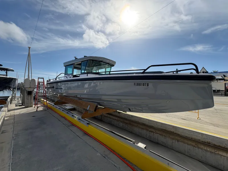 Slide: The Image of 2023 Axopar 28 AFT CABIN boat docked under a bright sky. - 4