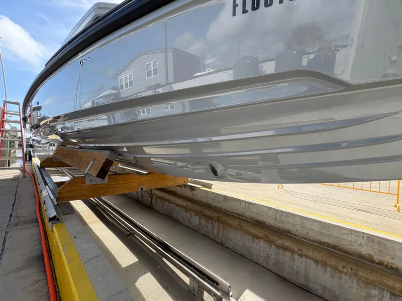 Slide: The Image of 2023 Axopar 28 AFT CABIN boat on dry dock, showcasing sleek hull design. - 6