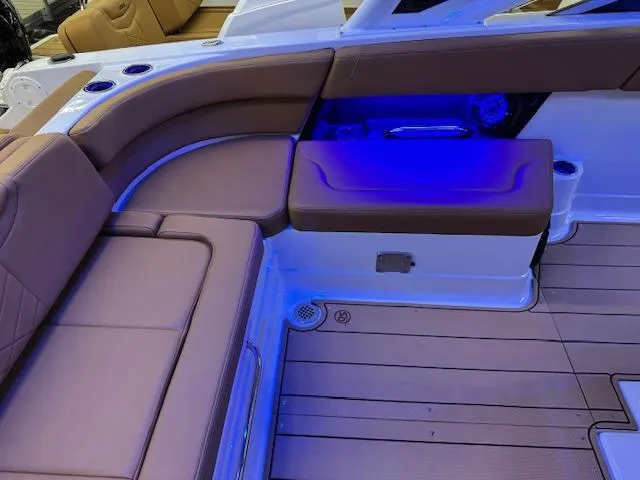 Slide: The Image of 2025 Chaparral 280 OSX boat interior with brown seating and blue LED lighting. - 15
