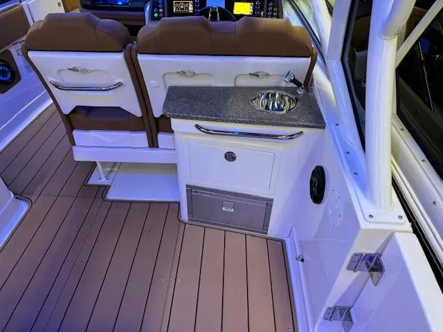 Slide: The Image of 2025 Chaparral 280 OSX boat interior with seating, sink, and storage. - 18