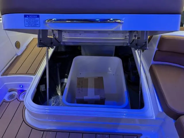 Slide: The Image of 2025 Chaparral 280 OSX boat storage compartment with blue lighting and seating area. - 19