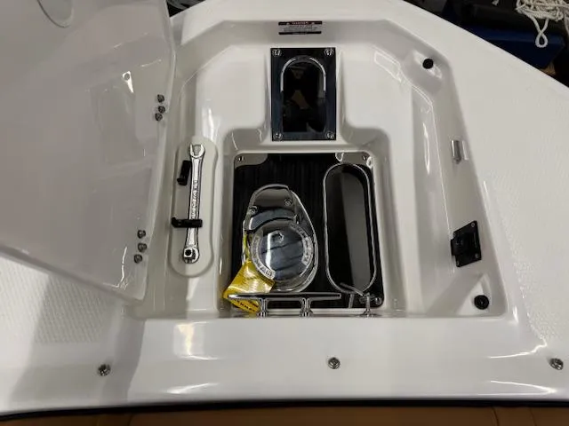 Slide: The Image of 2025 Chaparral 280 OSX boat storage compartment with open hatch and safety equipment. - 2