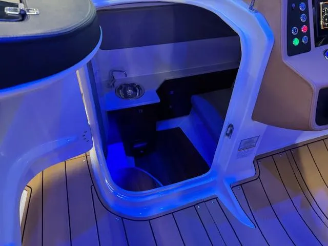 Slide: The Image of 2025 Chaparral 280 OSX cabin entrance with blue ambient lighting and wooden flooring. - 9