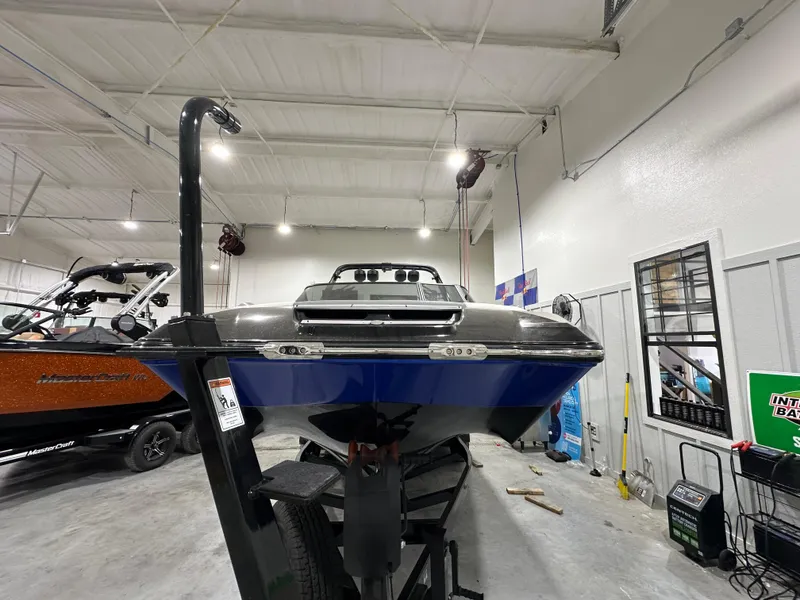 Slide: The Image of 2024 MasterCraft X26 boat in showroom, front view, blue and black design. - 6