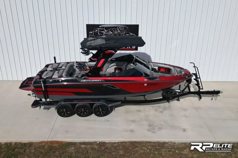 The Image of 2024 Centurion Ri245 boat in red and black on a trailer, side view. - 0