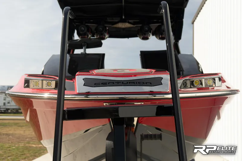 Slide: The Image of 2024 Centurion Ri245 boat, rear view, red and black design, parked outdoors. - 28