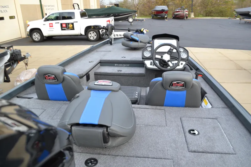 Slide: The Image of 2025 Ranger RT178 boat interior with gray and blue seating, dashboard, and storage compartments. - 2