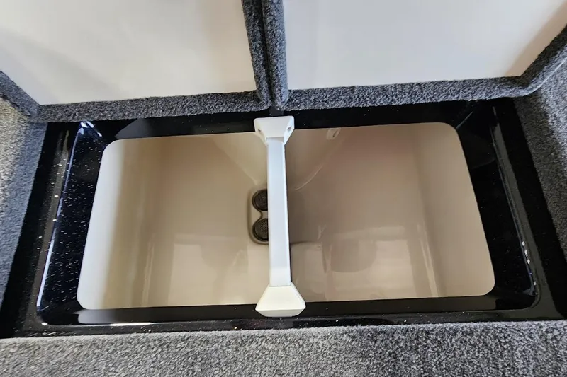 Slide: The Image of 2025 Ranger Z185 boat storage compartment with carpeted interior and white divider. - 12