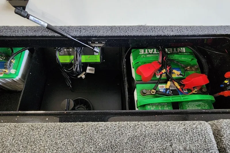 Slide: The Image of 2025 Ranger Z185 boat battery compartment with green batteries and wiring. - 13