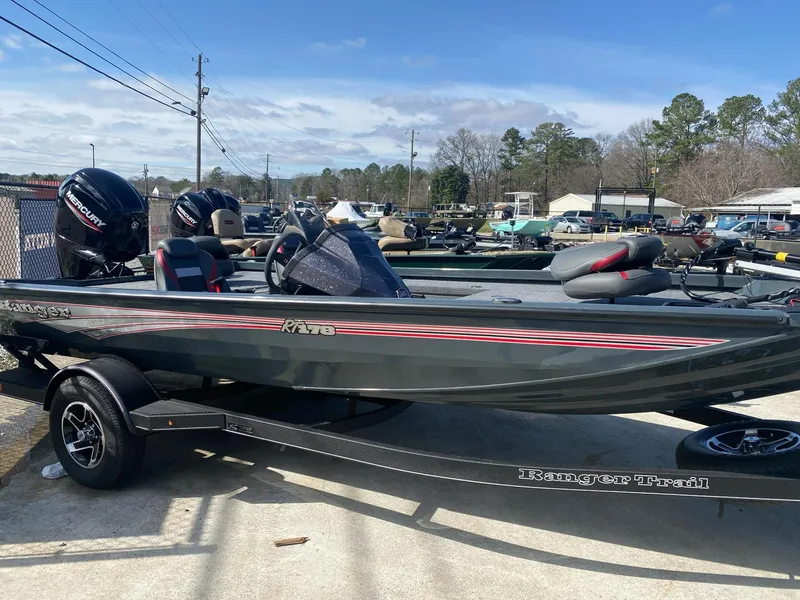 The Image of 2025 Ranger RT178 boat on trailer, parked outdoors, with trees and buildings in background. - 1