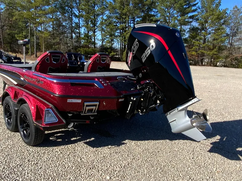 Slide: The Image of 2025 Ranger Z520 boat with powerful outboard motor, parked on gravel, surrounded by trees. - 19