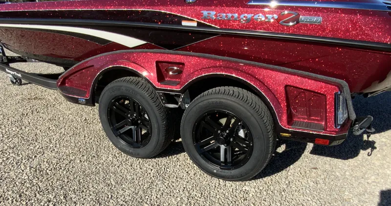 Slide: The Image of 2025 Ranger Z520 boat trailer with dual black wheels on gravel. - 3