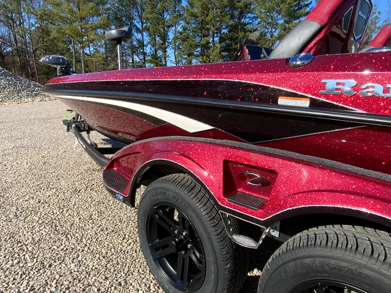 Slide: The Image of 2025 Ranger Z520 boat with sparkling red finish, parked on gravel, surrounded by trees. - 4