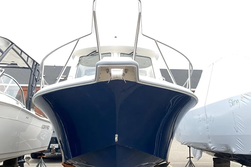 Slide: The Image of 2025 NorthCoast 235 HT boat, blue hull, docked between covered vessels. - 1