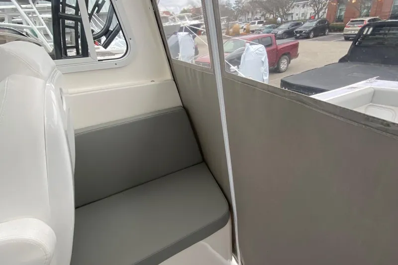 Slide: The Image of Interior view of 2025 NorthCoast 235 HT boat, featuring a cushioned seat and window. - 16