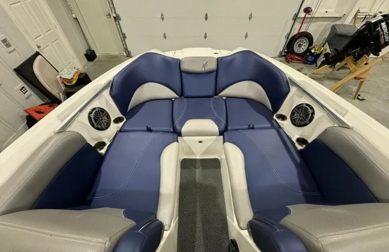 Slide: The Image of 2016 MasterCraft X46 boat interior with blue and gray seating, speakers, and cup holders. - 23