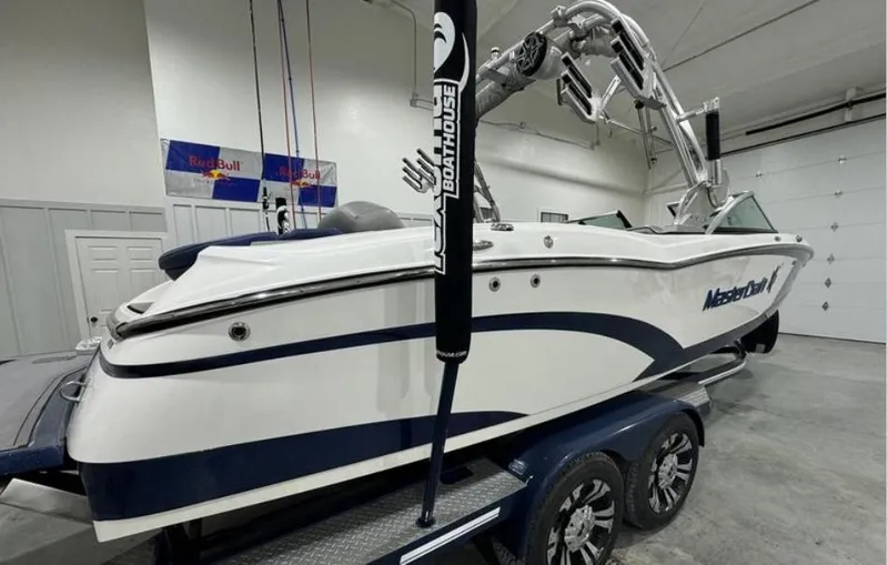 Slide: The Image of 2016 MasterCraft X46 boat in garage, white and blue design, on trailer. - 4
