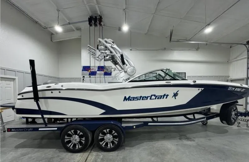 Slide: The Image of 2016 MasterCraft X46 boat in a garage, white and blue design, on a trailer. - 5