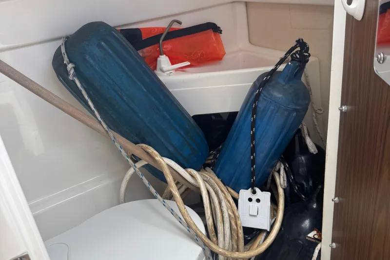 Slide: The Image of Storage compartment in a 2002 MacGregor 26X boat with blue fenders and ropes. - 13