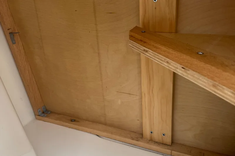 Slide: The Image of Wooden interior detail of a 2002 MacGregor 26X boat, showcasing structural elements. - 17