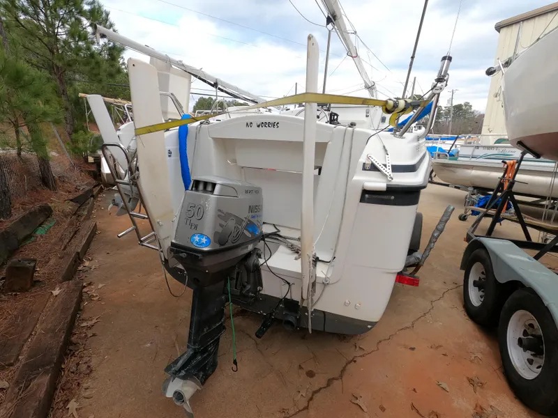 Slide: The Image of 2002 MacGregor 26X sailboat with outboard motor, parked on a trailer. - 2