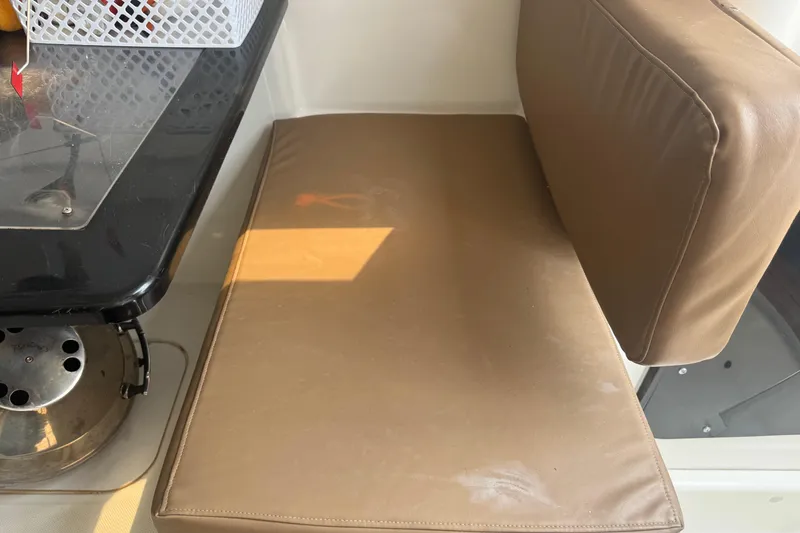 Slide: The Image of Brown cushioned seating and table inside a 2002 MacGregor 26X boat cabin. - 7