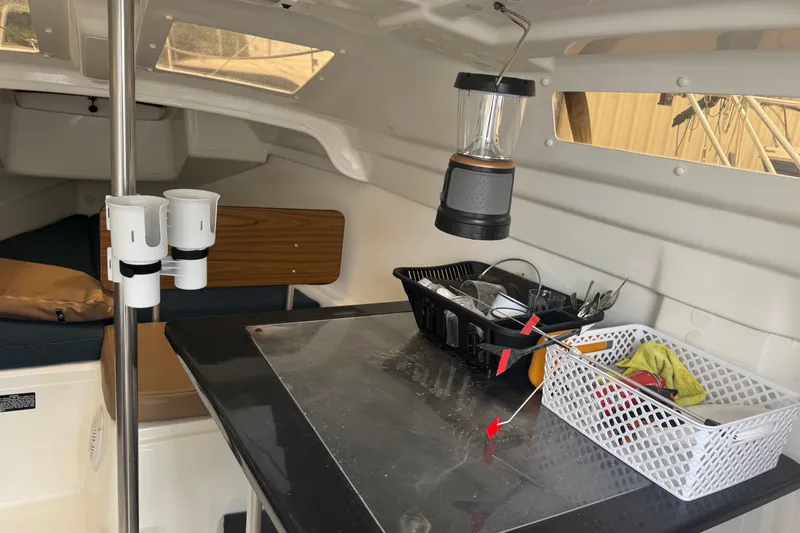 Slide: The Image of Interior of a 2002 MacGregor 26X sailboat with organized storage and a hanging lantern. - 8