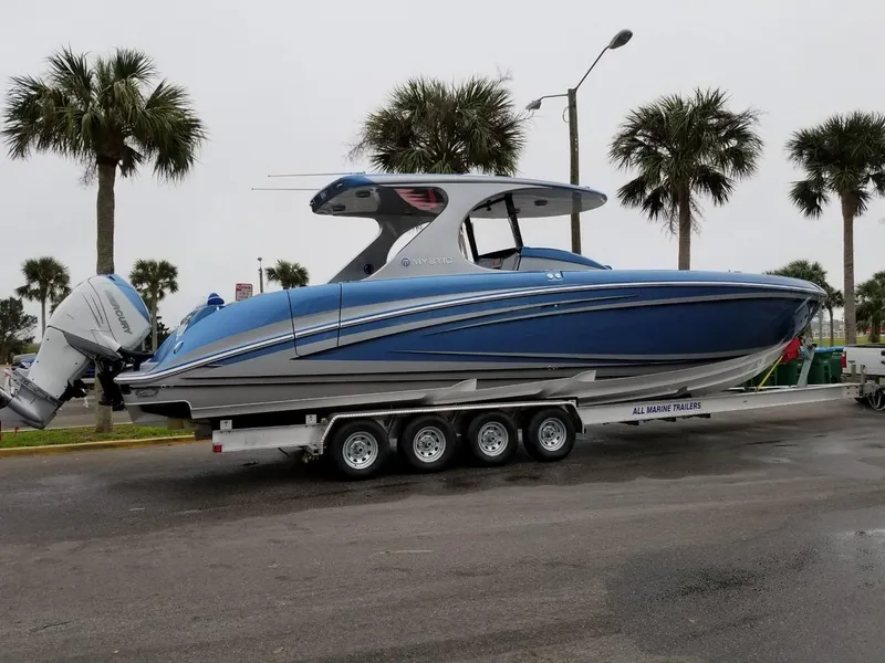 Slide: The Image of 2018 Mystic Powerboats M4200 on trailer, blue hull, parked near palm trees. - 27