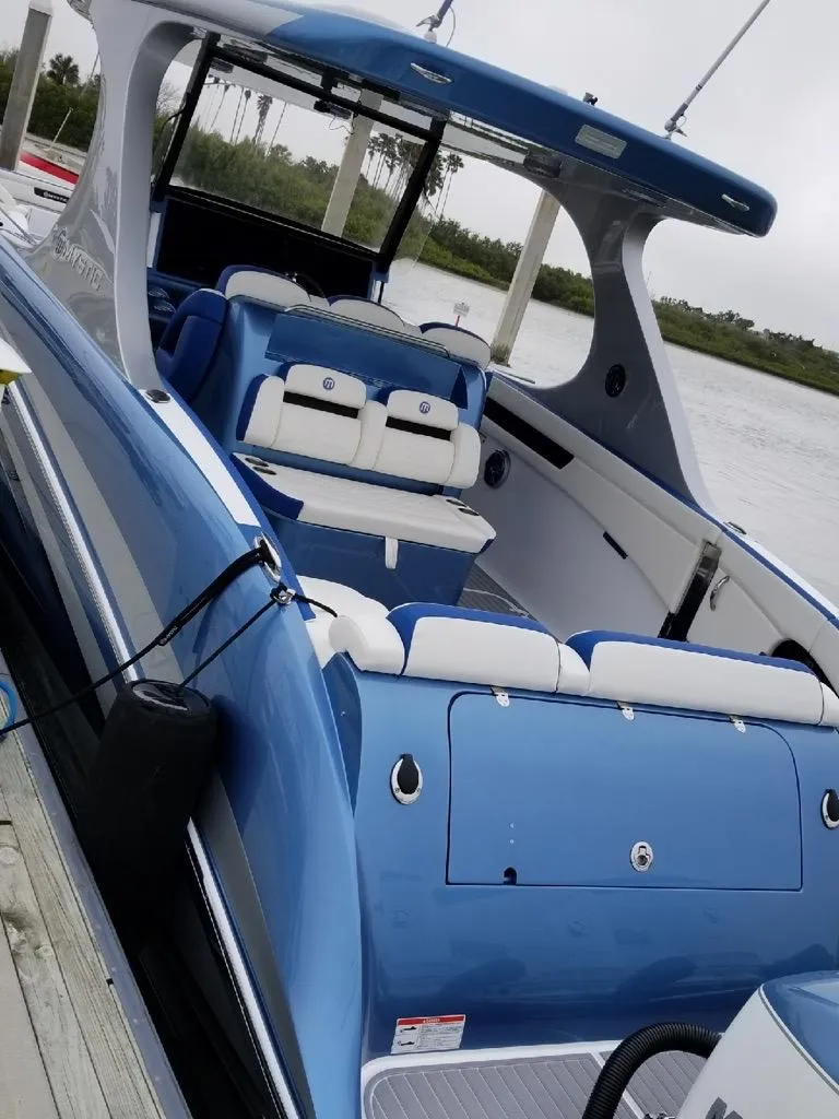 Slide: The Image of 2018 Mystic Powerboats M4200, sleek blue design, luxury seating, docked by the water. - 30