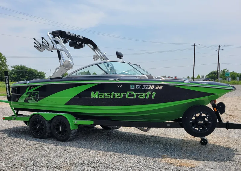 Slide: The Image of 2012 MasterCraft X25 boat in green and black on a trailer. - 10