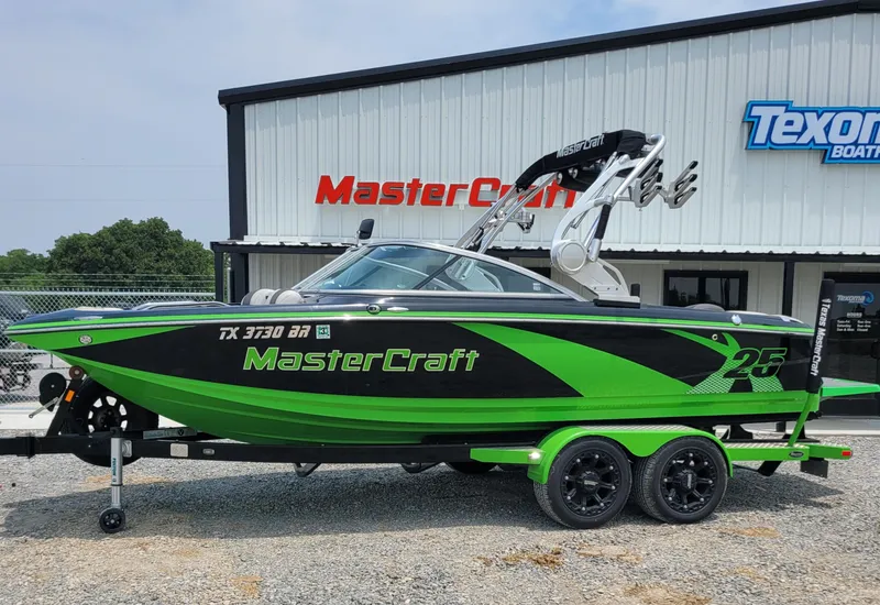 Slide: The Image of 2012 MasterCraft X25 boat in green and black, parked outside dealership. - 3