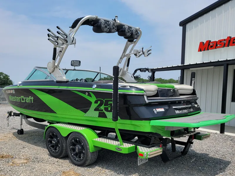 Slide: The Image of 2012 MasterCraft X25 boat, green and black, on trailer near MasterCraft building. - 5