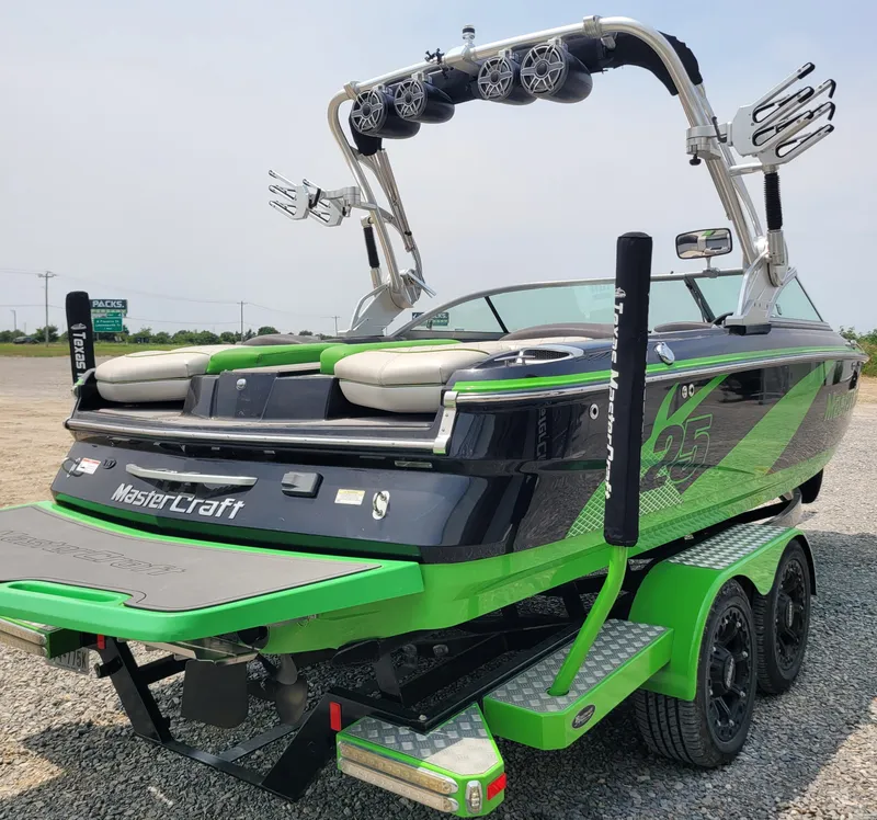 Slide: The Image of 2012 MasterCraft X25 boat with green and black design on a trailer. - 7
