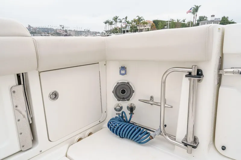 Slide: The Image of 2019 Boston Whaler 330 Outrage boat interior with storage, speaker, and coiled hose. - 23