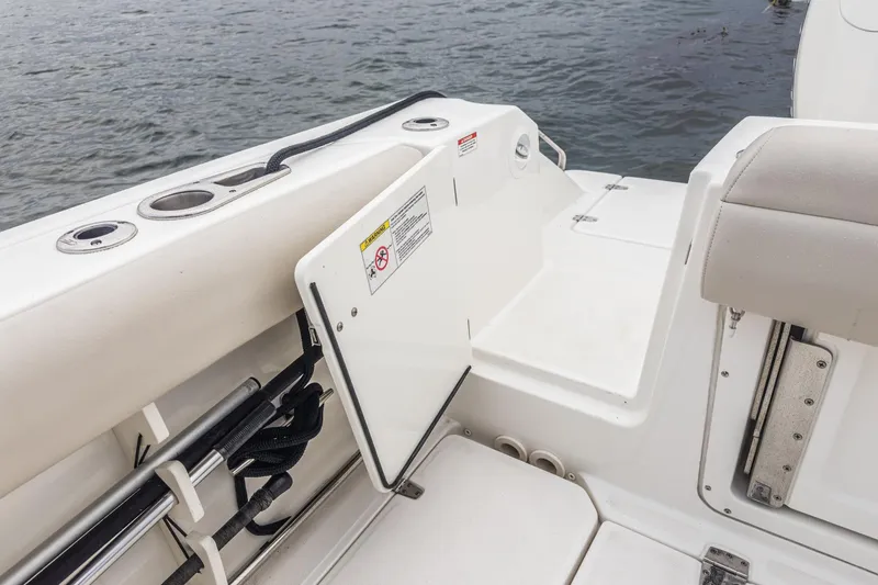 Slide: The Image of 2019 Boston Whaler 330 Outrage boat deck with seating and storage, near water. - 31